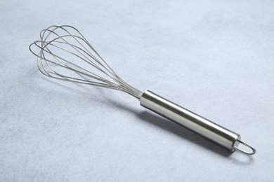 Metal whisk on gray table. Kitchen tool