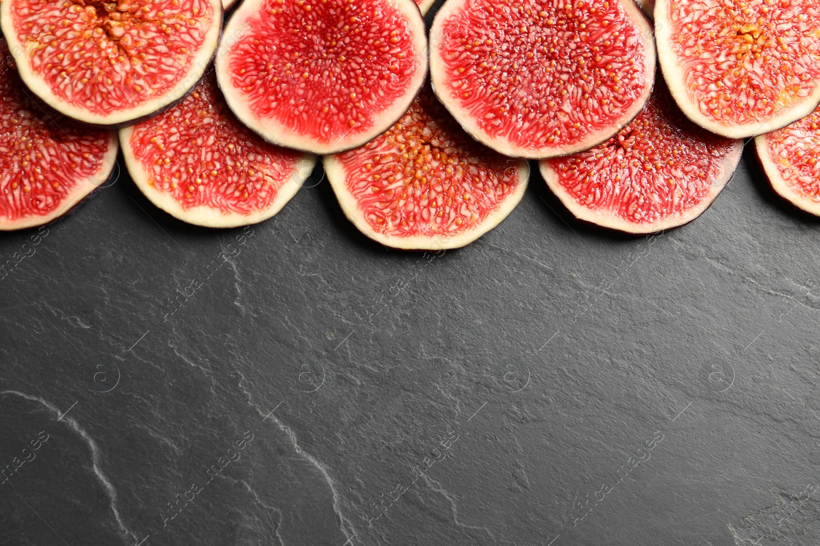 Photo of Pieces of fresh ripe figs on grey textured table, flat lay. Space for text