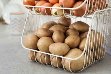 Photo of Container with potatoes and onions on grey kitchen counter. Orderly storage