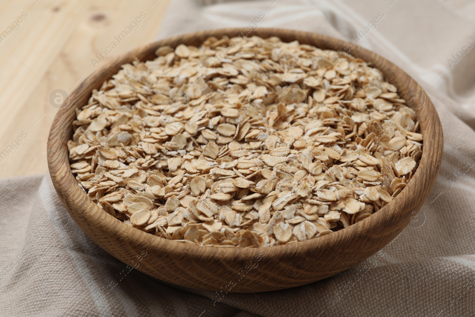 Photo of Wooden bowl with oatmeal on table, closeup