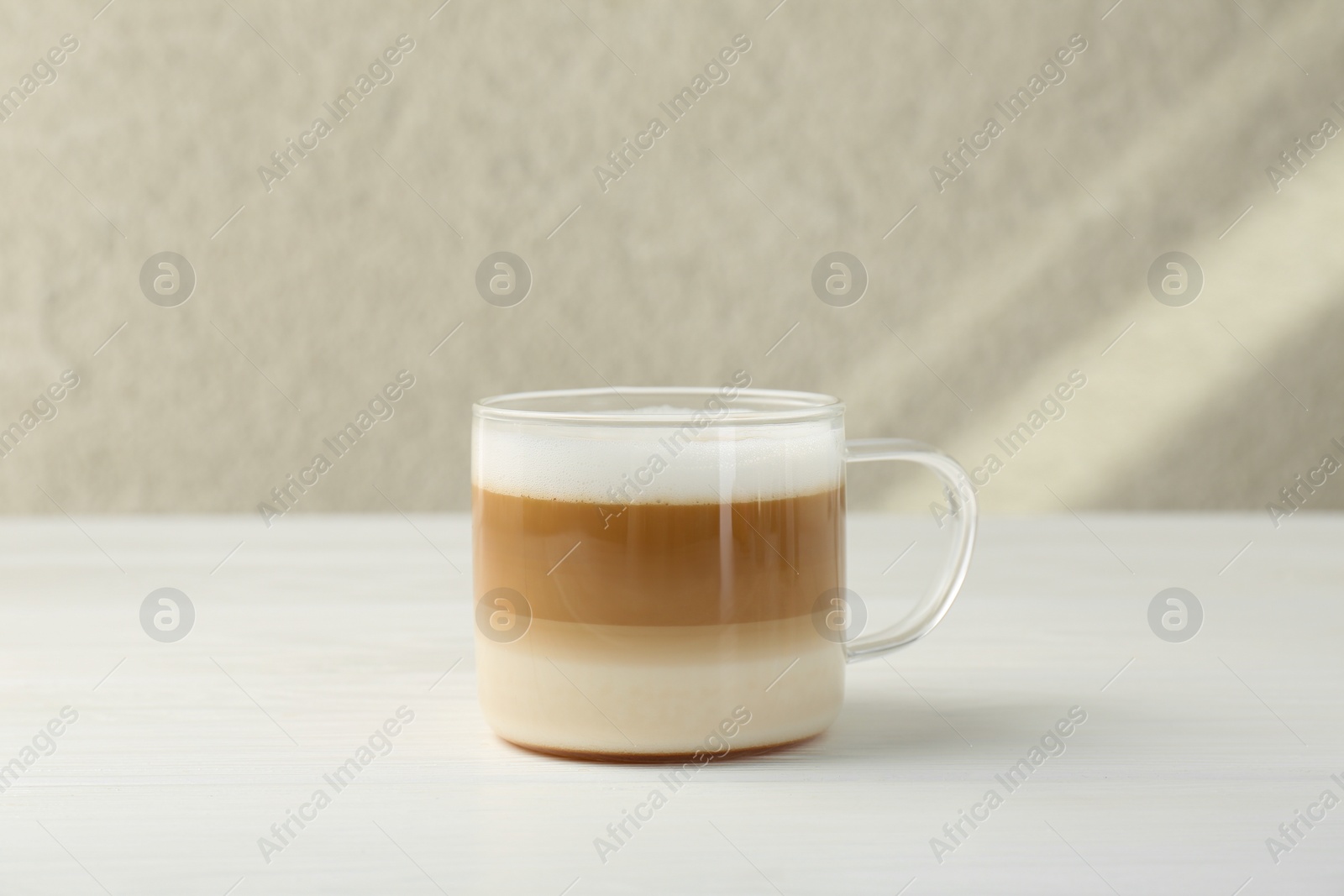 Photo of Aromatic coffee in glass cup on white wooden table