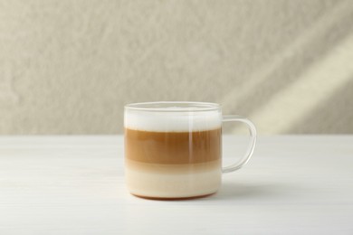 Photo of Aromatic coffee in glass cup on white wooden table