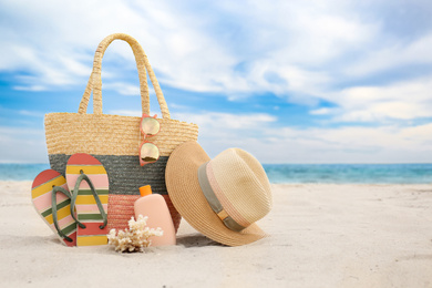 Photo of Different stylish beach objects and coral on sand near sea. Space for text