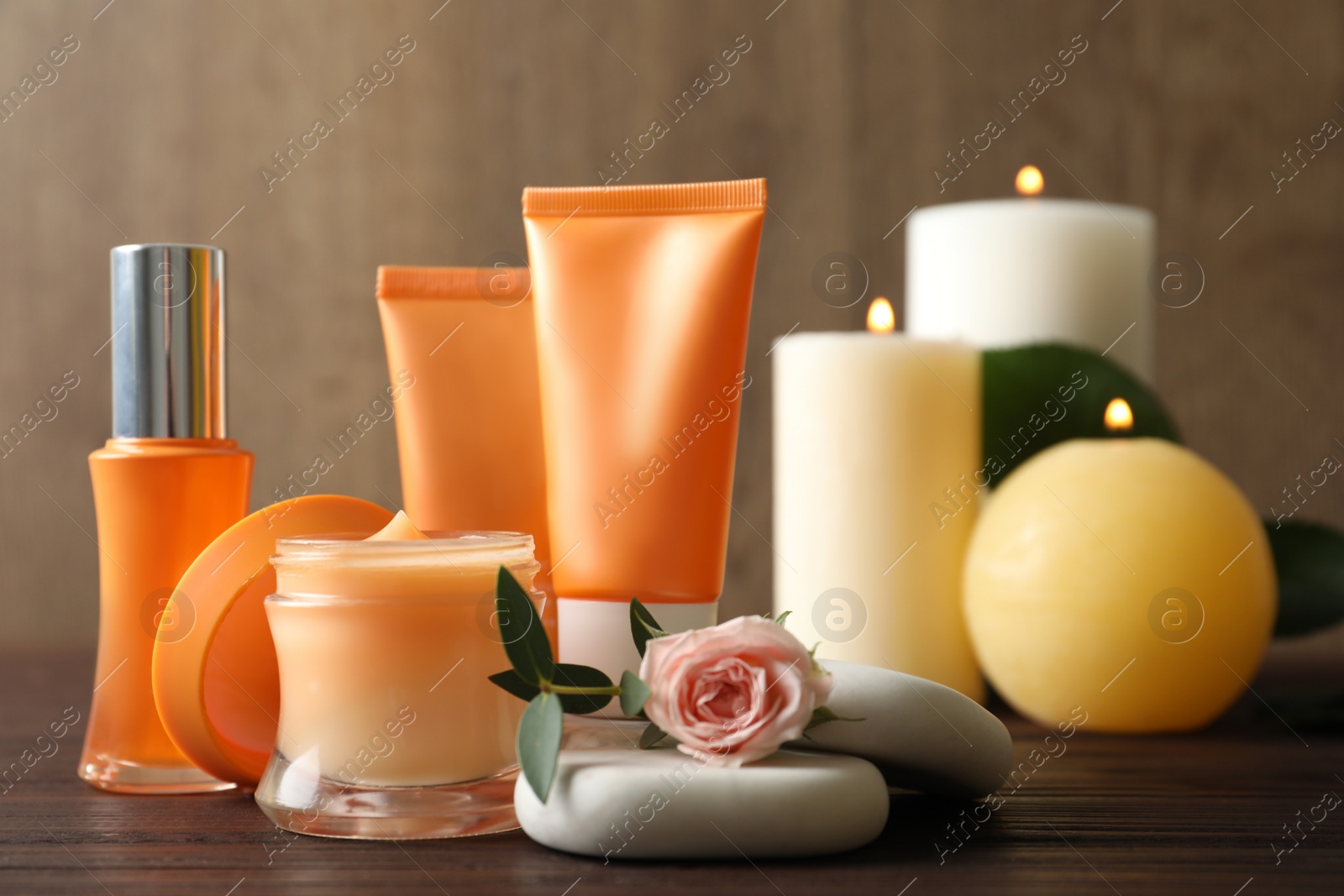 Photo of Composition with cosmetic products, spa stones and burning candles on wooden table