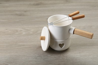 Fondue set on wooden table, space for text