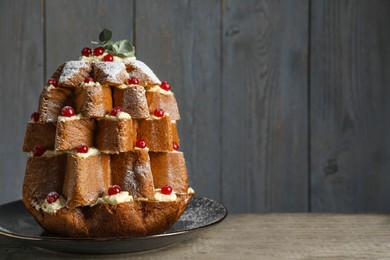 Photo of Delicious Pandoro Christmas tree cake with powdered sugar and berries on wooden table. Space for text