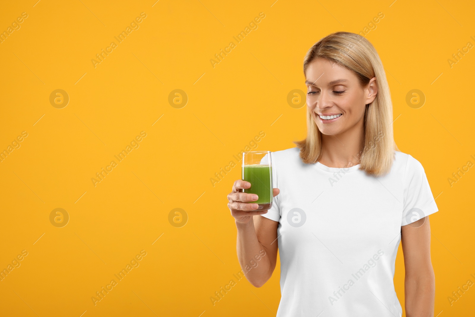 Photo of Happy woman with glass of fresh celery juice on orange background. Space for text