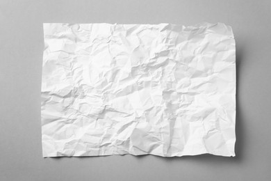 Photo of Sheet of white crumpled paper on grey background, top view