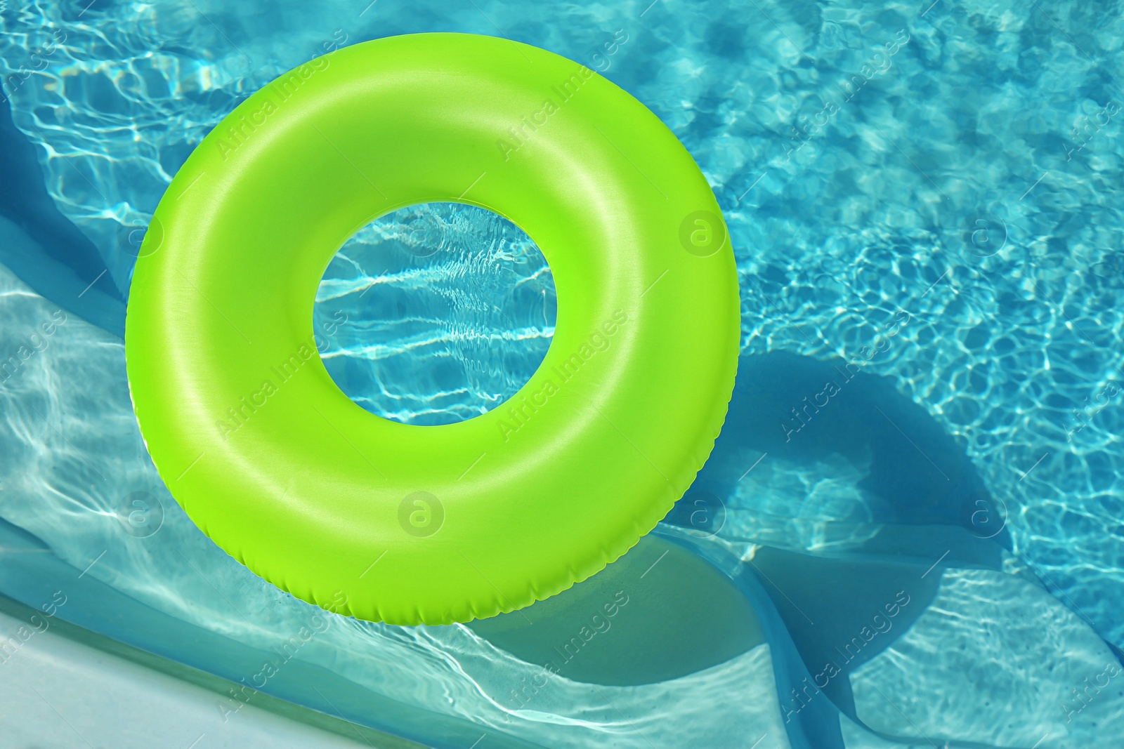 Photo of Bright inflatable ring floating in swimming pool on sunny day. Space for text