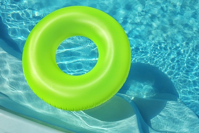 Bright inflatable ring floating in swimming pool on sunny day. Space for text