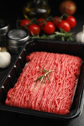 Photo of Plastic container with fresh minced meat on black table, closeup