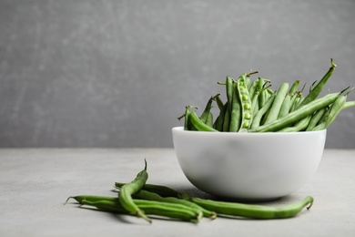 Photo of Fresh green beans on light grey table. Space for text