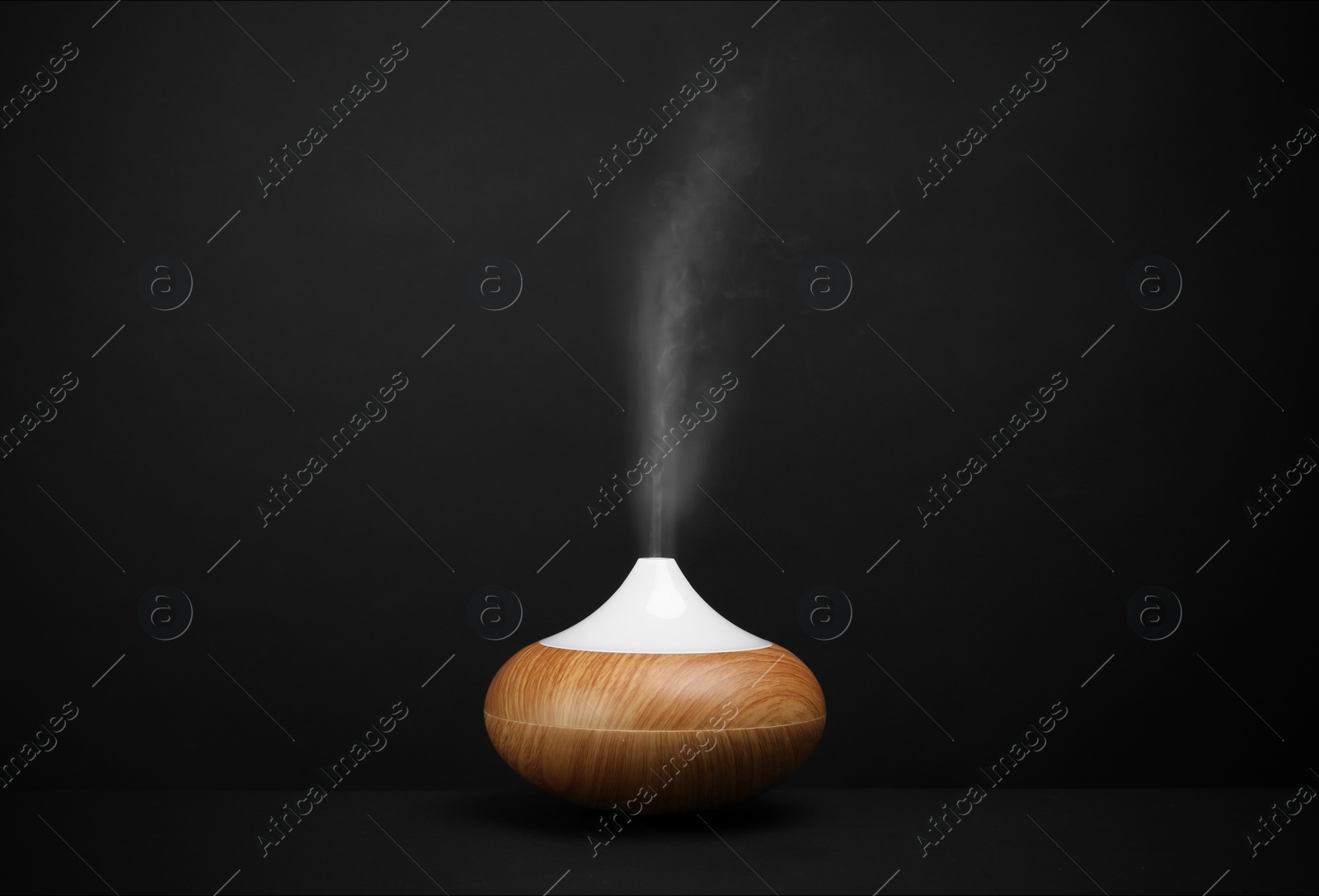 Photo of Modern essential oil diffuser on black background. Space for text