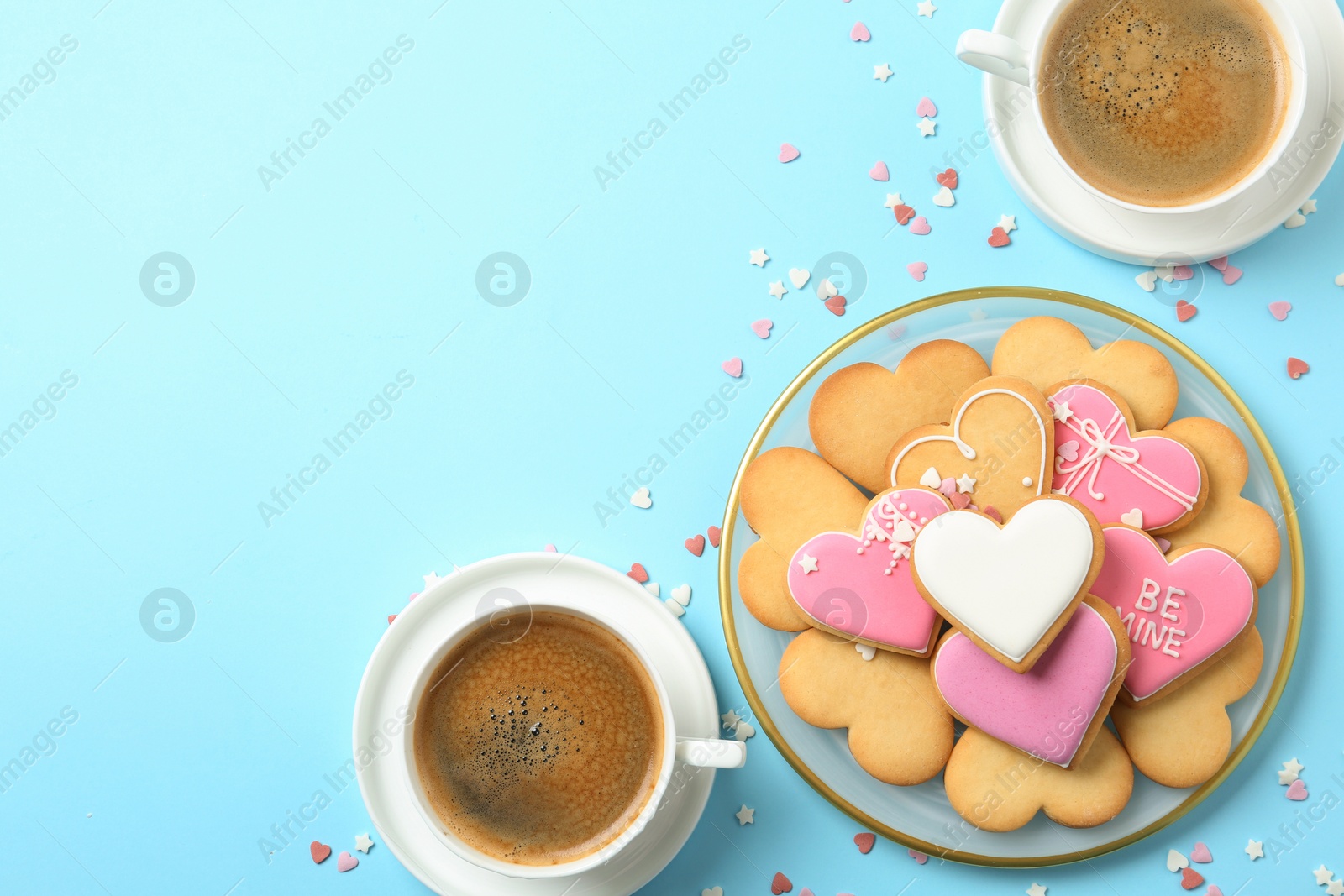 Photo of Romantic breakfast with heart shaped cookies and cups of coffee on color background, flat lay. Space for text