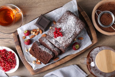 Photo of Tasty chocolate sponge cake served on wooden table, flat lay