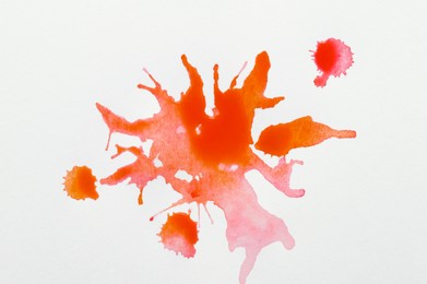 Orange ink blots on white canvas, top view