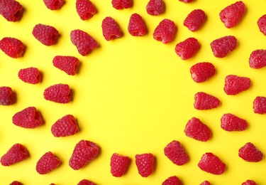 Frame made with delicious ripe raspberries on yellow background. Space for text