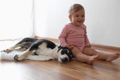 Photo of Adorable baby and cute dog on faux fur rug indoors