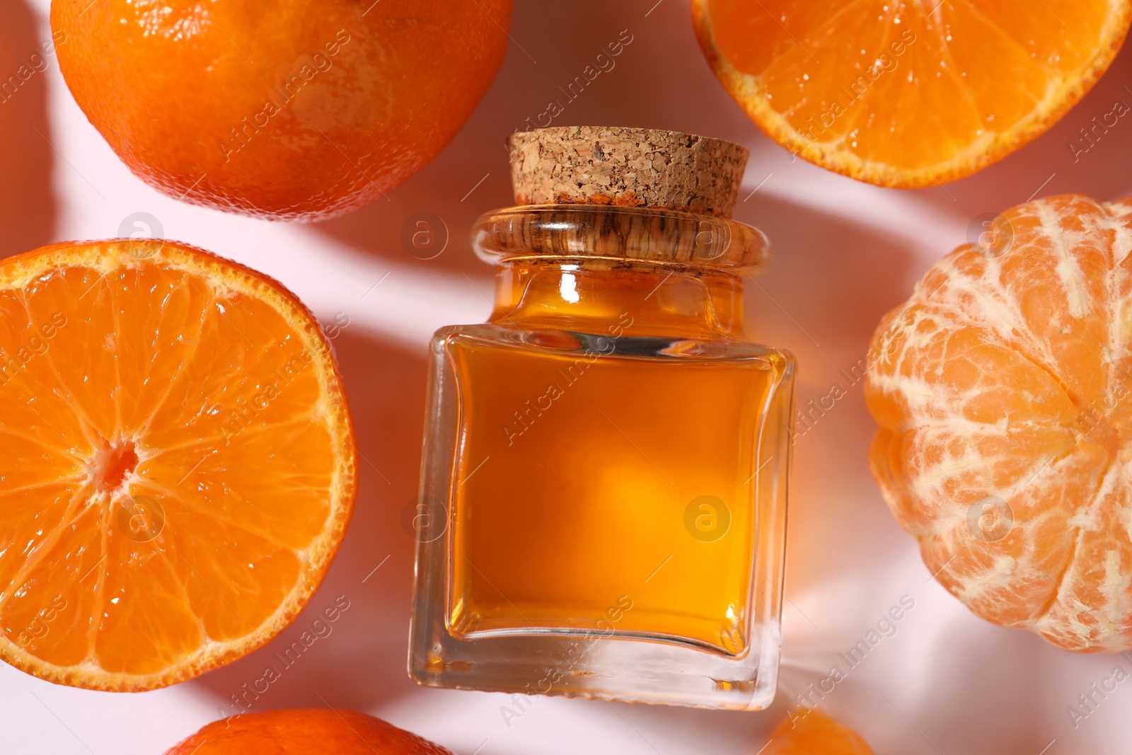 Photo of Aromatic tangerine essential oil in bottle and citrus fruits on white table, flat lay