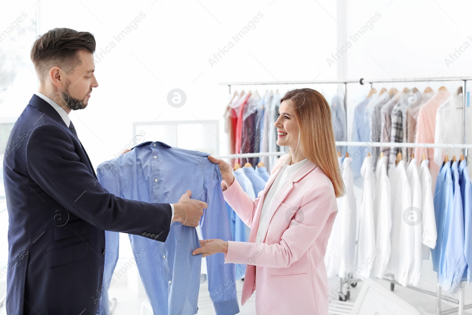 Photo of Young businessman giving shirt to dry-cleaner's worker