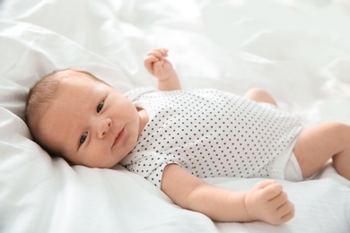 Photo of Adorable newborn baby lying on bed sheet