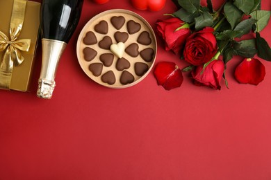Flat lay composition with heart shaped chocolate candies on red background, space for text. Valentine's day celebration
