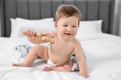 Happy baby boy with blanket and rattle sitting on bed at home
