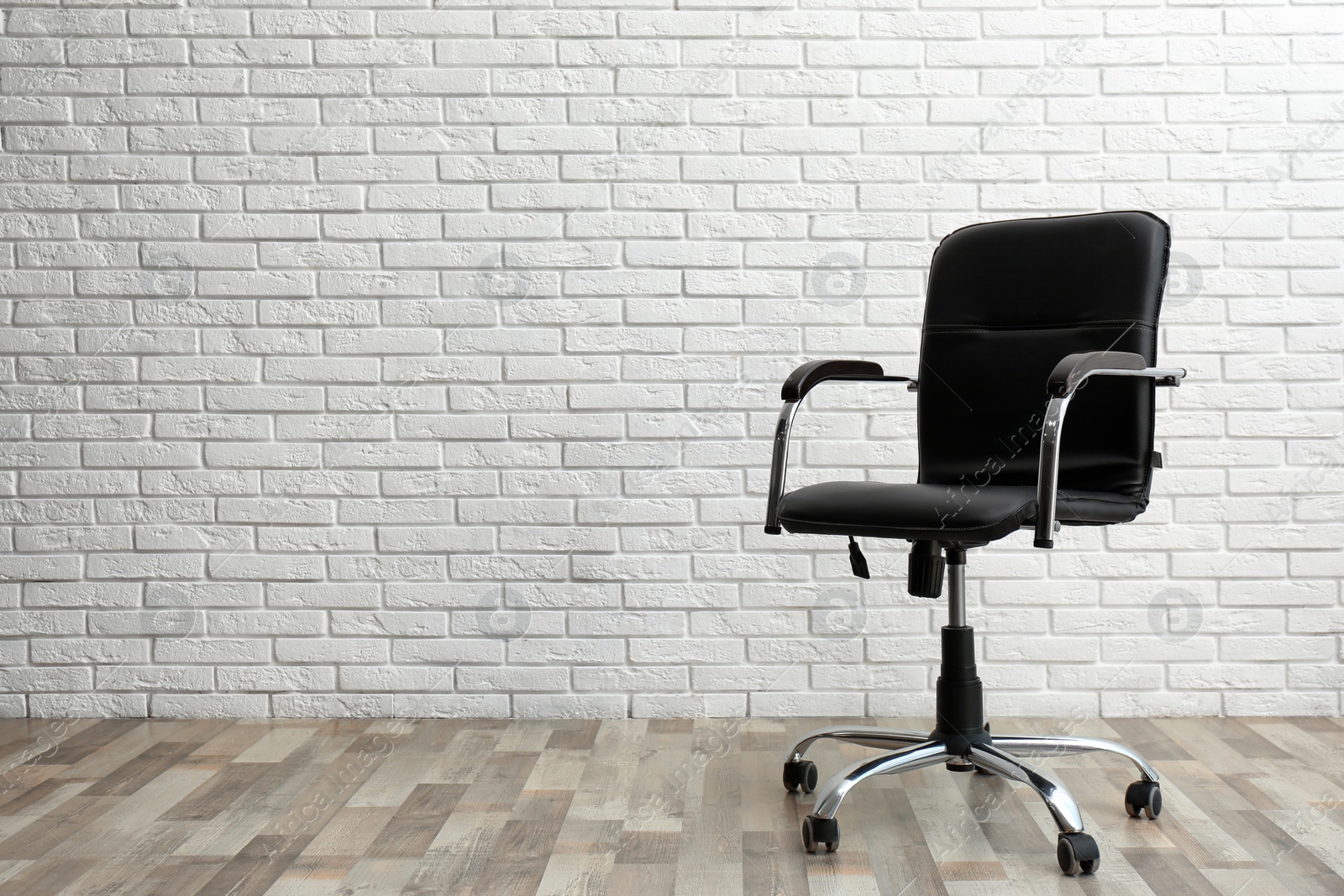 Photo of Comfortable office chair near white brick wall indoors. Space for text