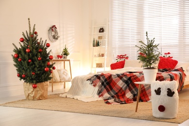 Photo of Beautiful green Christmas trees in bedroom. Interior design