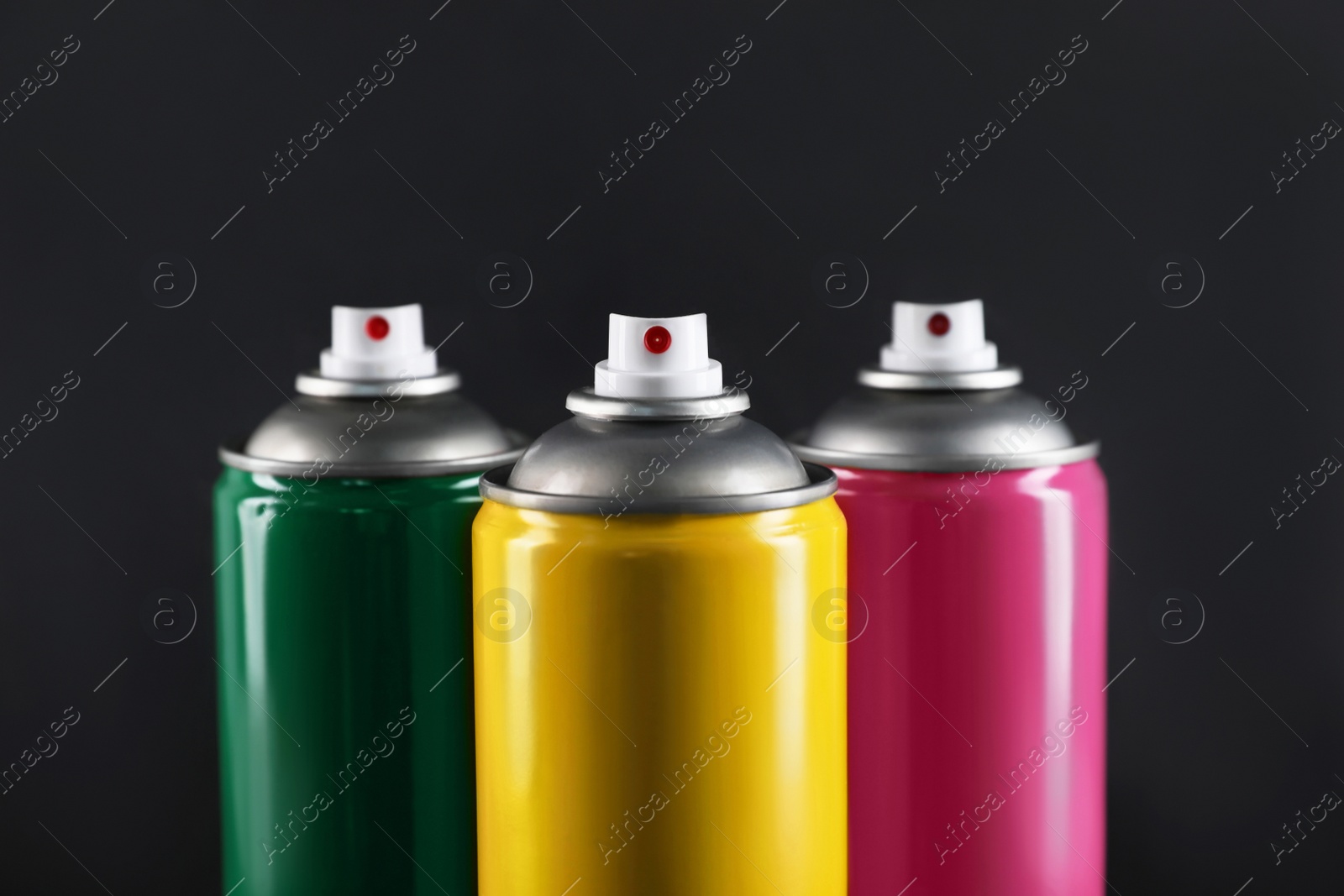 Photo of Colorful cans of spray paints on black background, closeup