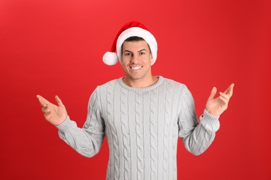 Handsome man wearing Santa hat on red background