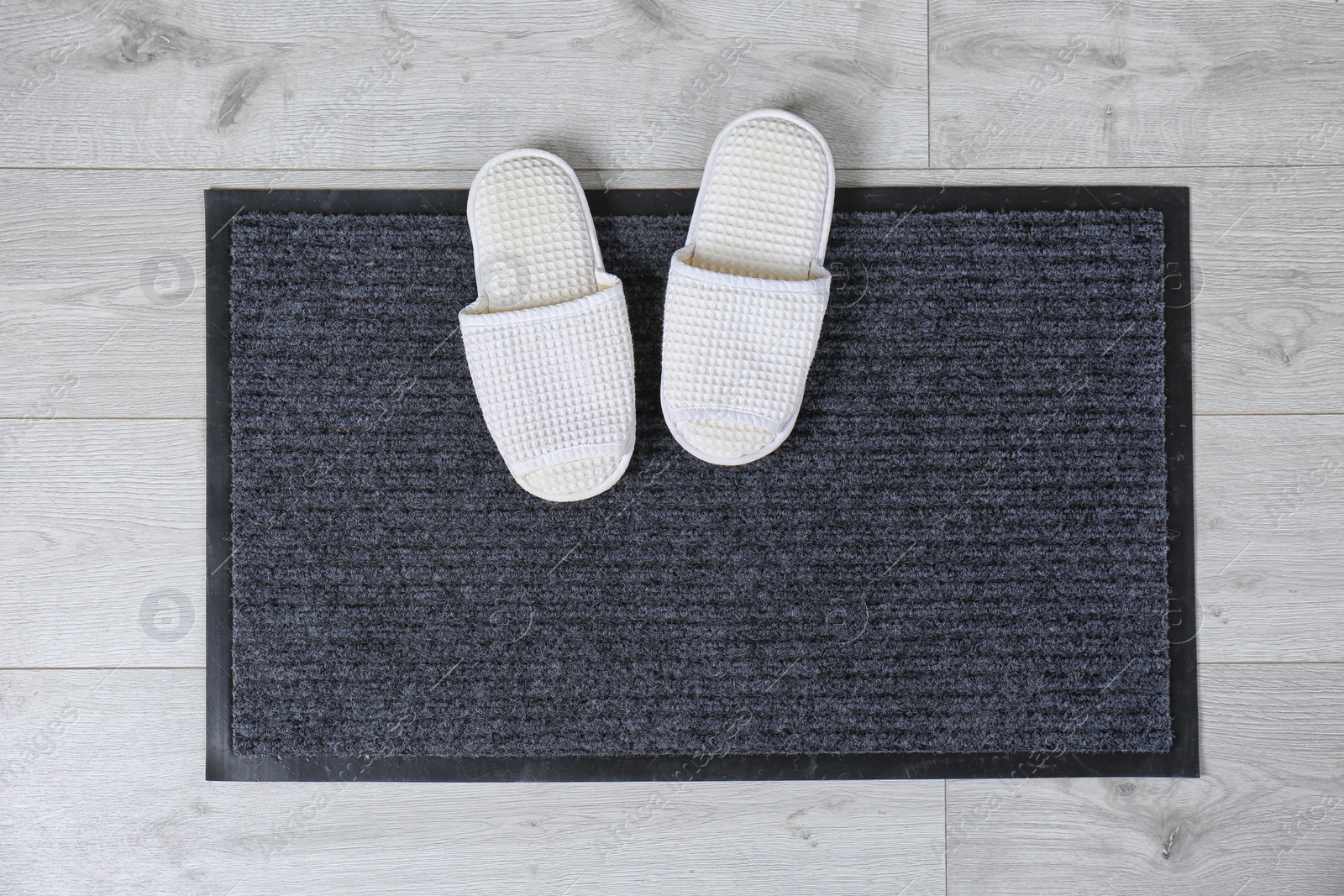 Photo of Door mat and slippers on floor, top view. Space for text