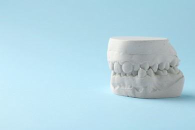 Dental model with gums on light blue background, space for text. Cast of teeth