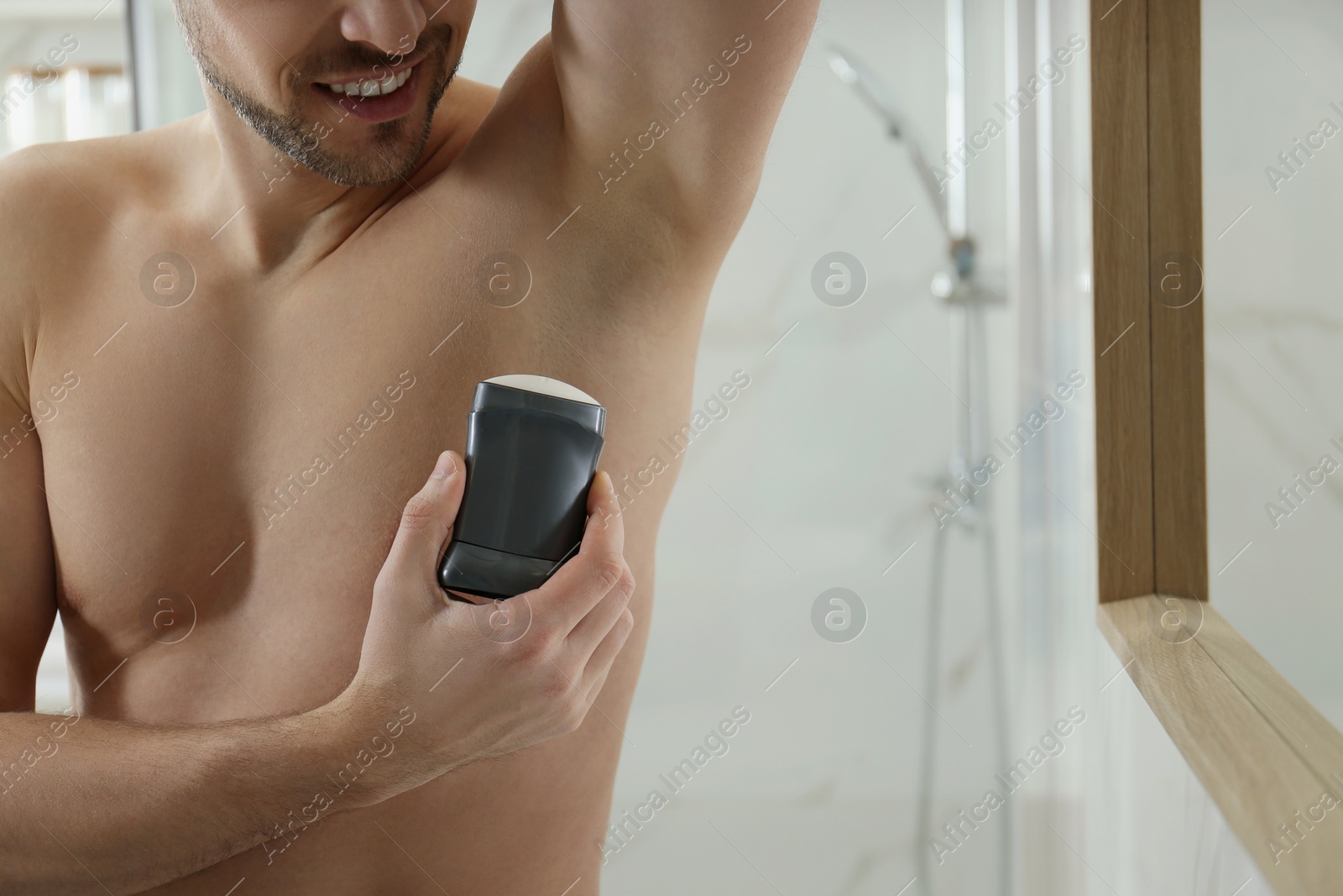 Photo of Man applying deodorant in bathroom, closeup. Space for text