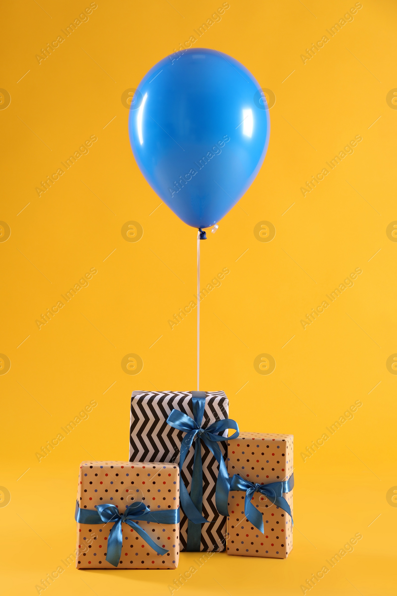 Photo of Three gift boxes and balloon on yellow background