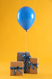 Photo of Three gift boxes and balloon on yellow background