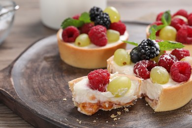 Photo of Delicious tartlets with berries on wooden table, closeup