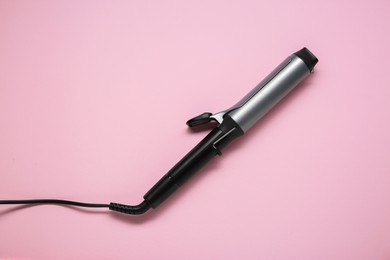 Photo of Hair styling appliance. One curling iron on pink background, top view
