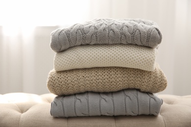 Stack of folded warm sweaters on couch indoors