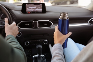 Couple with thermos in car, closeup view
