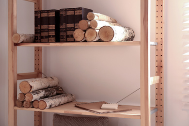 Shelving unit with stacked firewood and books near wall. Idea for interior design