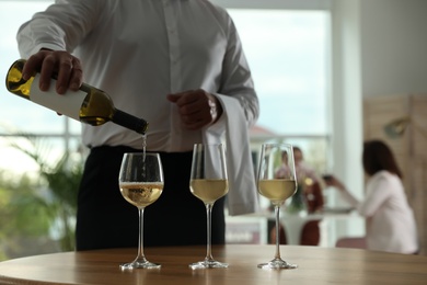 Photo of Waiter pouring wine into glass in restaurant, closeup
