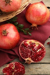 Photo of Fresh pomegranates and green leaves on wooden table, top view