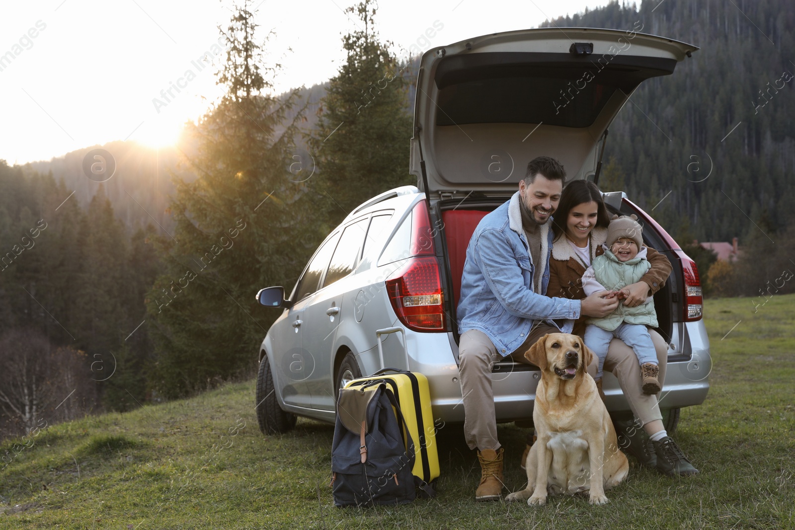 Photo of Parents, their daughter and dog near car in mountains, space for text. Family traveling with pet