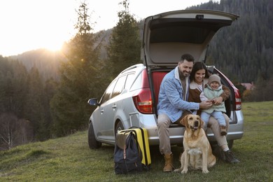 Parents, their daughter and dog near car in mountains, space for text. Family traveling with pet