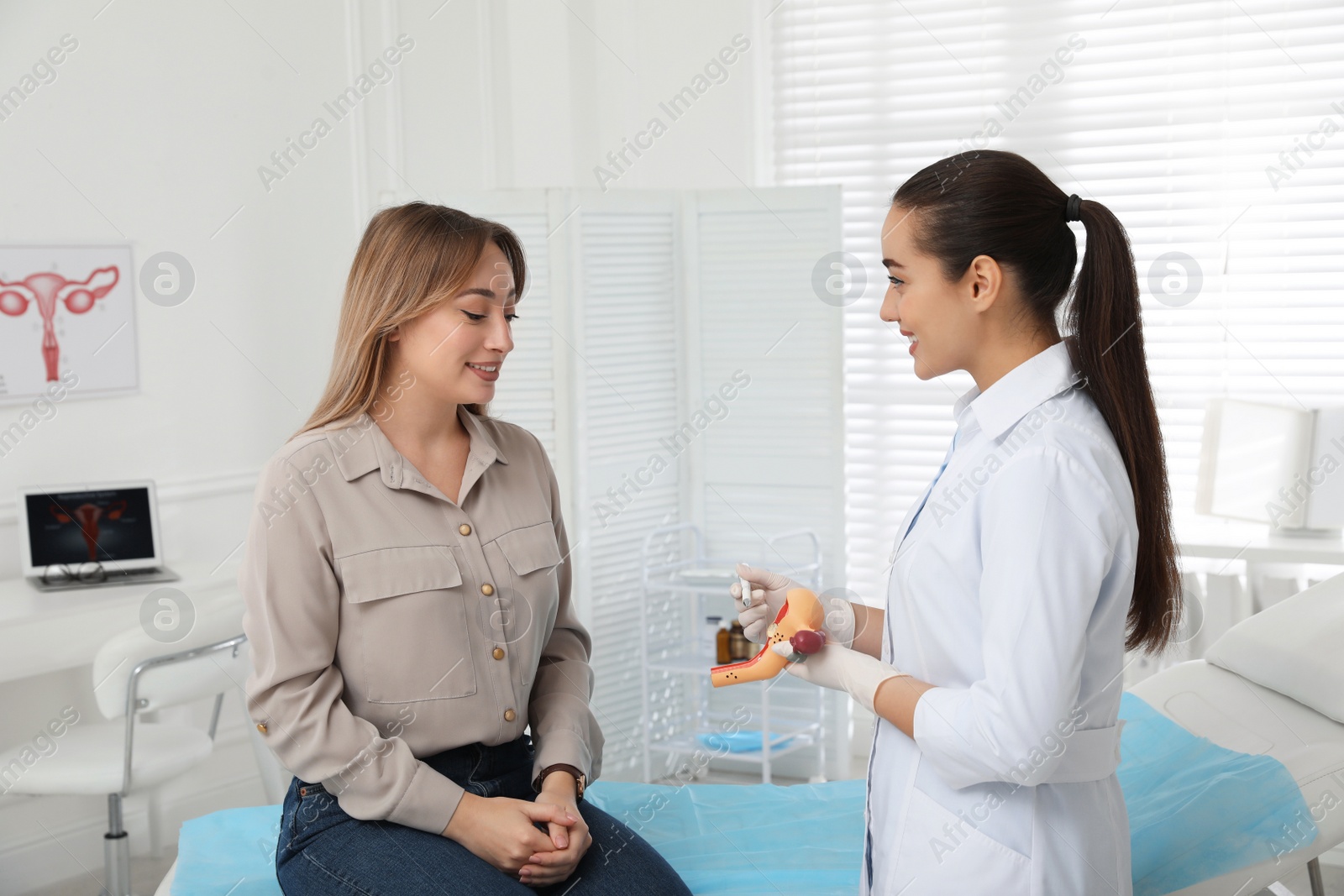 Photo of Gynecologist demonstrating model of female reproductive system to young woman in clinic