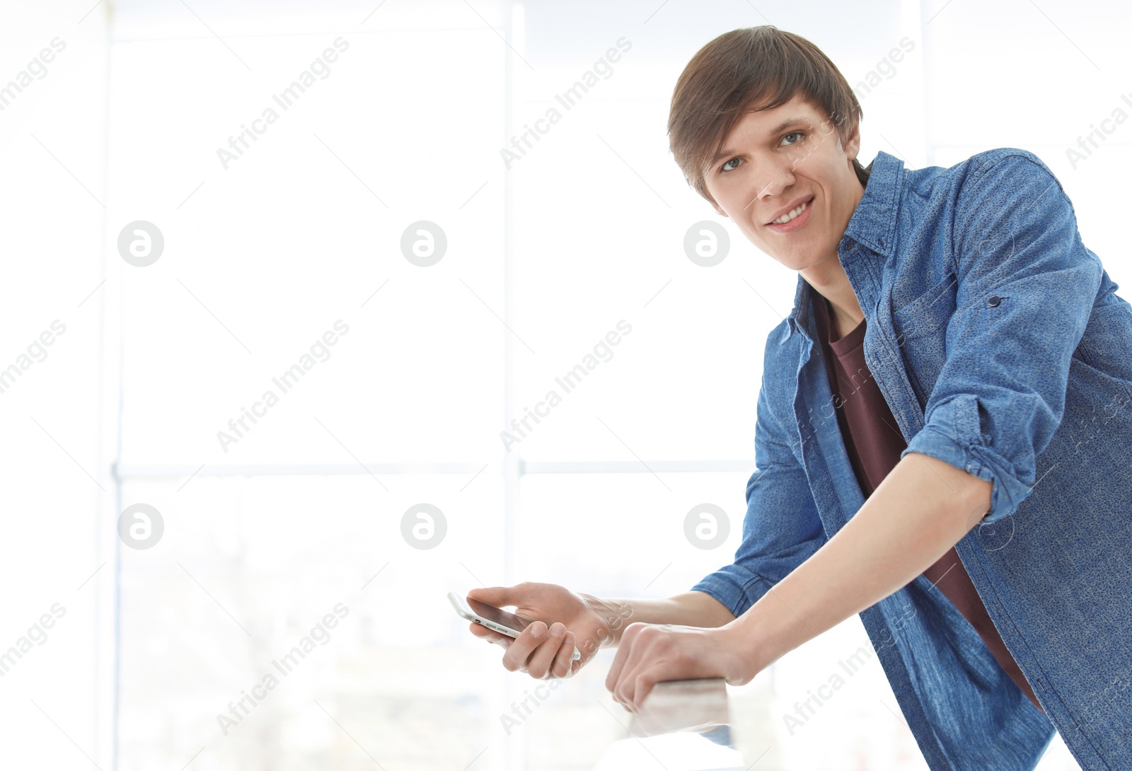 Photo of Portrait of confident young man with mobile phone, indoors