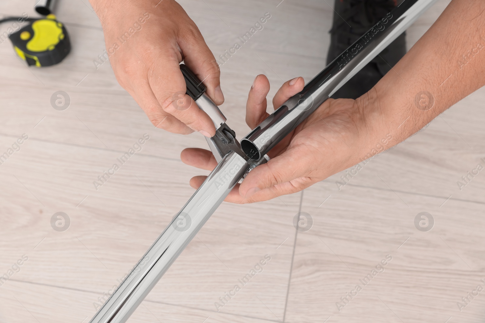 Photo of Worker installing new metal pipes indoors, closeup