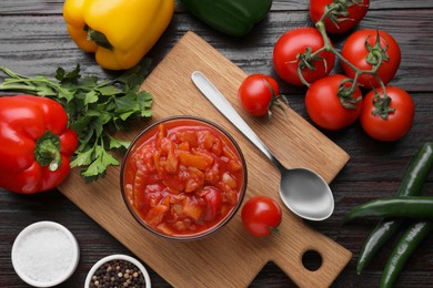 Delicious lecho in bowl and fresh ingredients on wooden table, flat lay