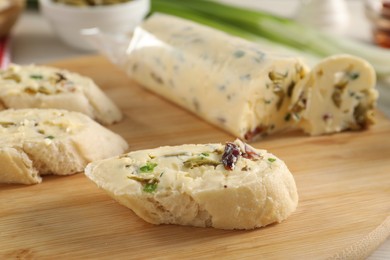 Photo of Tasty butter with olives, green onion, chili pepper and bread on table, closeup